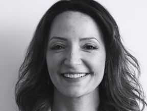Lawyer Luana Lacerda with shoulder-length hair smiling, wearing a blazer and necklace, in black and white.