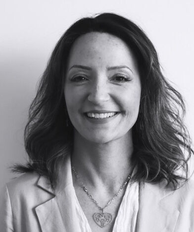 Lawyer Luana Lacerda with shoulder-length hair smiling, wearing a blazer and necklace, in black and white.